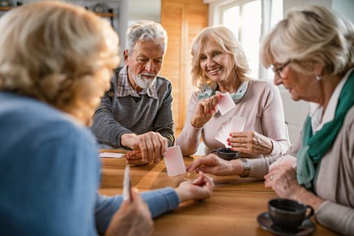 Small group mature friends enjoying while playing cards home